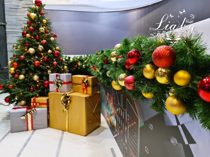 украшение телестудии к новому году: украшение стола ведущего новогодней елью с подарками, хвойная гирлянда, композиция из подарков с подсветкой