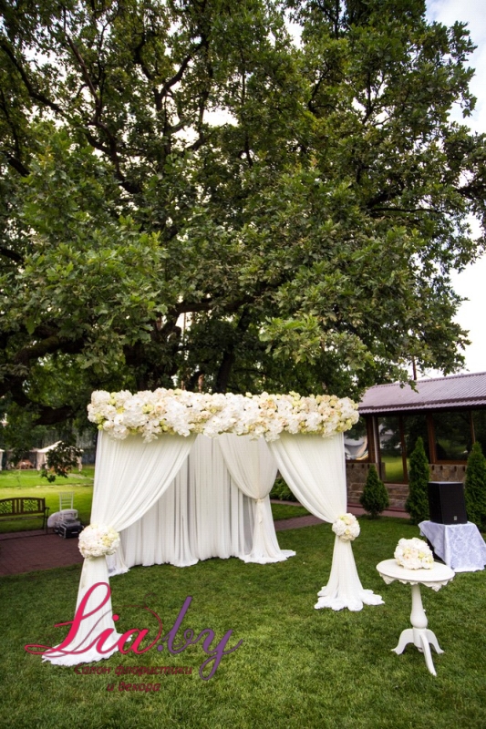 Красивый белый шатер на свадьбу с оформлением цветами и столик для росписи