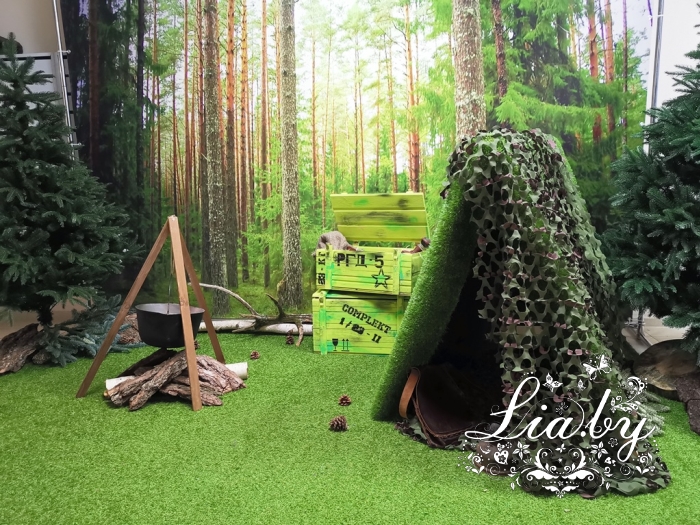 фотозона в стиле землянки-блиндажа военного в лесу, с кострищем и котелком, ящиками с боезапасами, с елями и фоном с печатью лесного пейзажа