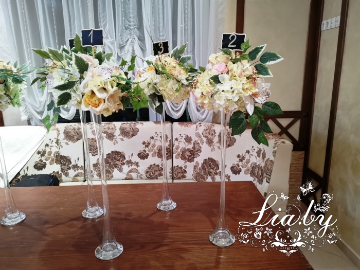 высокие вазы с цветами и номерами столов на свадьбу
