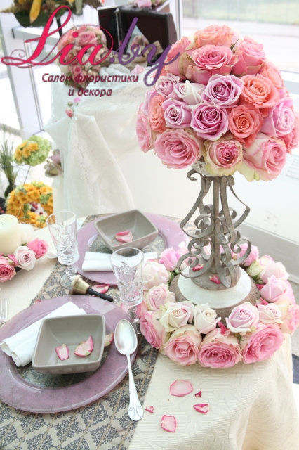 Аккуратная, красивая композиция из розовых роз на подсвечнике для украшения свадебного банкета