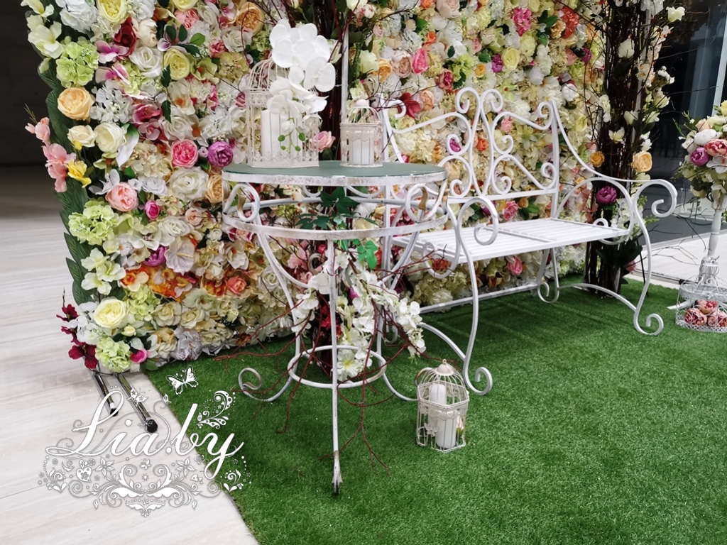 Кованный стол с сопутствующим декором на большой цветочной фотозоне