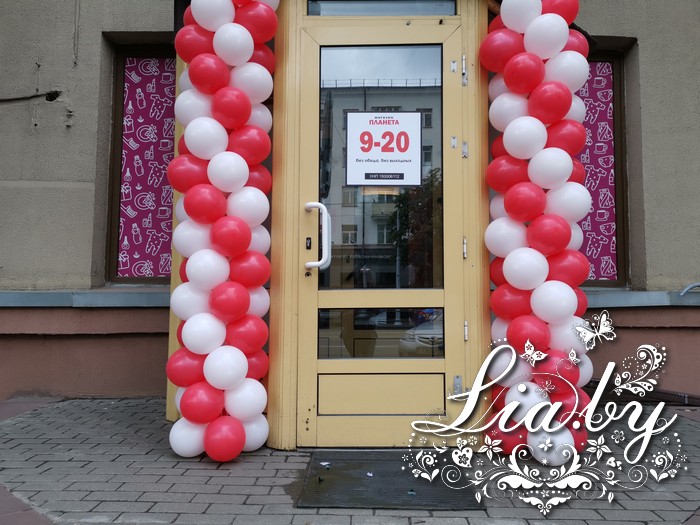 Столбы из воздушных шаров белого и красного цвета для украшения входа в магазин