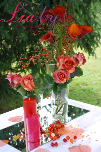 Цветочная инсталляция на столе дарения на свадьбе из красных и алых цветов.