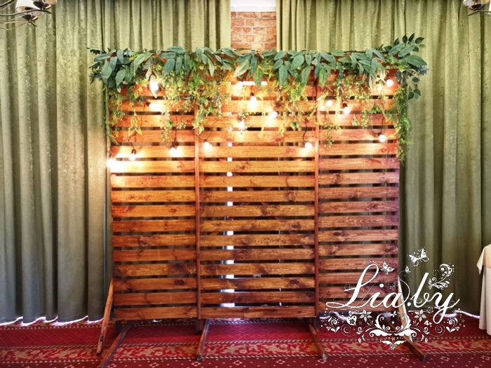 деревянный фон , ретро-гирляндой, белым столиком и зеленью на свадьбу в Дрозды клаб