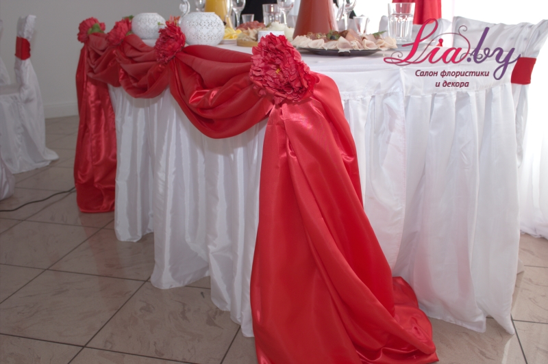Юбка стола молодых украшена тканями и пышными цветами (красная свадьба)