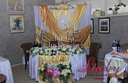 Украшение стола для молодых в золотом цвете с цветочной композицией и гербом