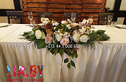 украшение стола на свадьбу белой скатертью и цветами на краю скатерти.