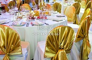 Украшение свадебного зала в бело-золотом цвете. Стулья украшены золотыми получехлами одетыми на полный белый чехол