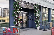 украшение входа в цветочный магазин композициями из искусственных цветов и зелени обрамляющих вход в вазах