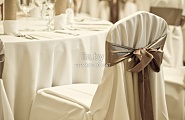 Украшение стульев белой тканью и коричневым бантом