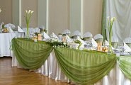 Стол для молодых украшенный зеленой тканью, цветами и свечами