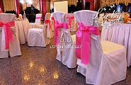Украшение стульев розовыми бантами поверх полных чехлов